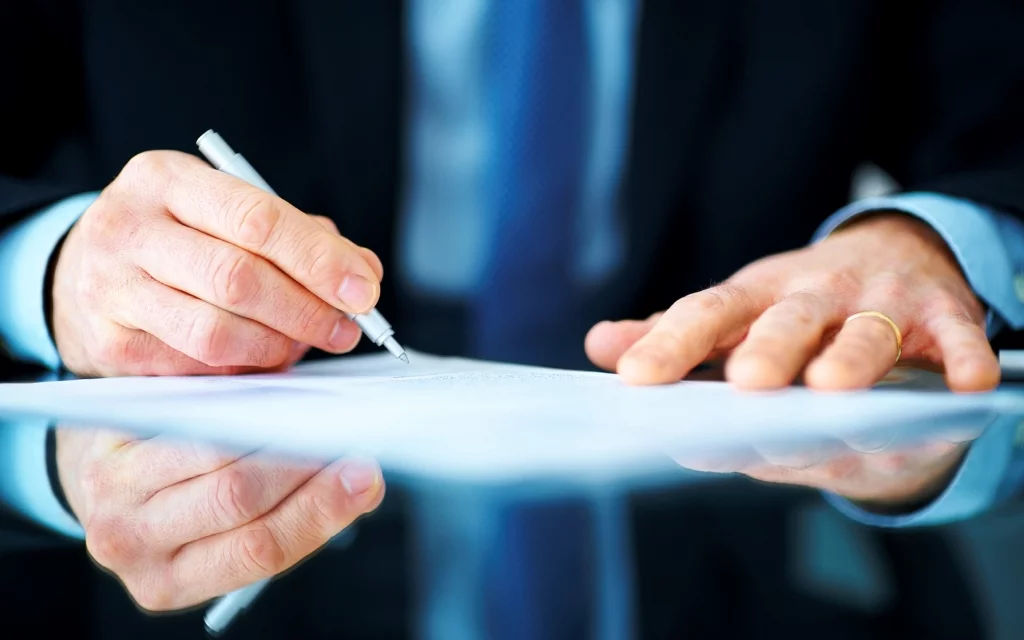 Business man hand signing on document at desk Allpe Empresa y Consultoría de Medio Ambiente, Acústica, Topografía e Ingeniería en Madrid